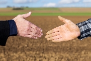 Handschlag zwischen Geschäftsmann und Landwirt vor Acker Handschlag zwischen Geschäftsmann und Landwirt vor Acker